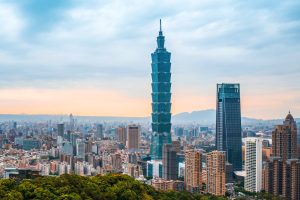 Taipei 101 above dense urban development with other skyscrapers and mountains in the background.