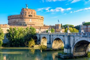 An angled view of Ponte Sant'Angelo with Castel Sant'Angelo in the background and the Tiber visible.