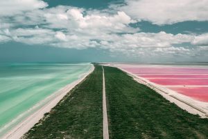 Las Coloradas from the air with a coastal strip, turquoise sea and pink water basins.