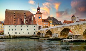 Steinerne Brücke in Regensburg mit Brückturm und Altstadt am Donauufer bei Abendlicht
