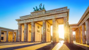 Brandenburg Gate viewed from an angle with sunlight shining between the columns